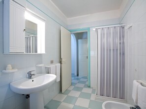 A bathroom with a sink, mirror, shower, and checkered floor.