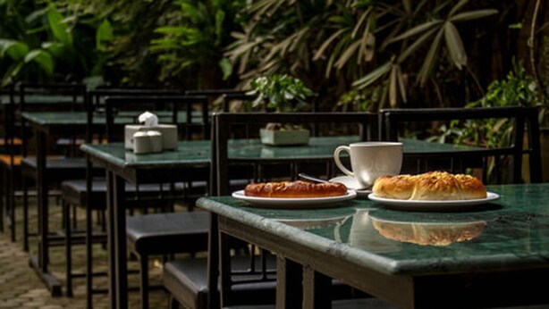 An outdoor café with tables and chairs, a plate of food, and a cup. - Hotel Jagat (Kathmandu)