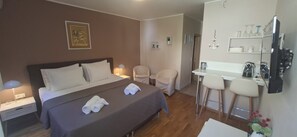 A hotel room with a bed, two chairs, a desk, and a coffee machine. - Carol Rooms (Trogir)