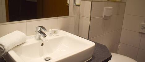 A bathroom with a white sink, a mirror, a toilet, and a towel rack.