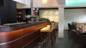 Un interior de restaurante con una barra de madera, zona de asientos y un cartel que dice 'Restaurante Jonathan'.