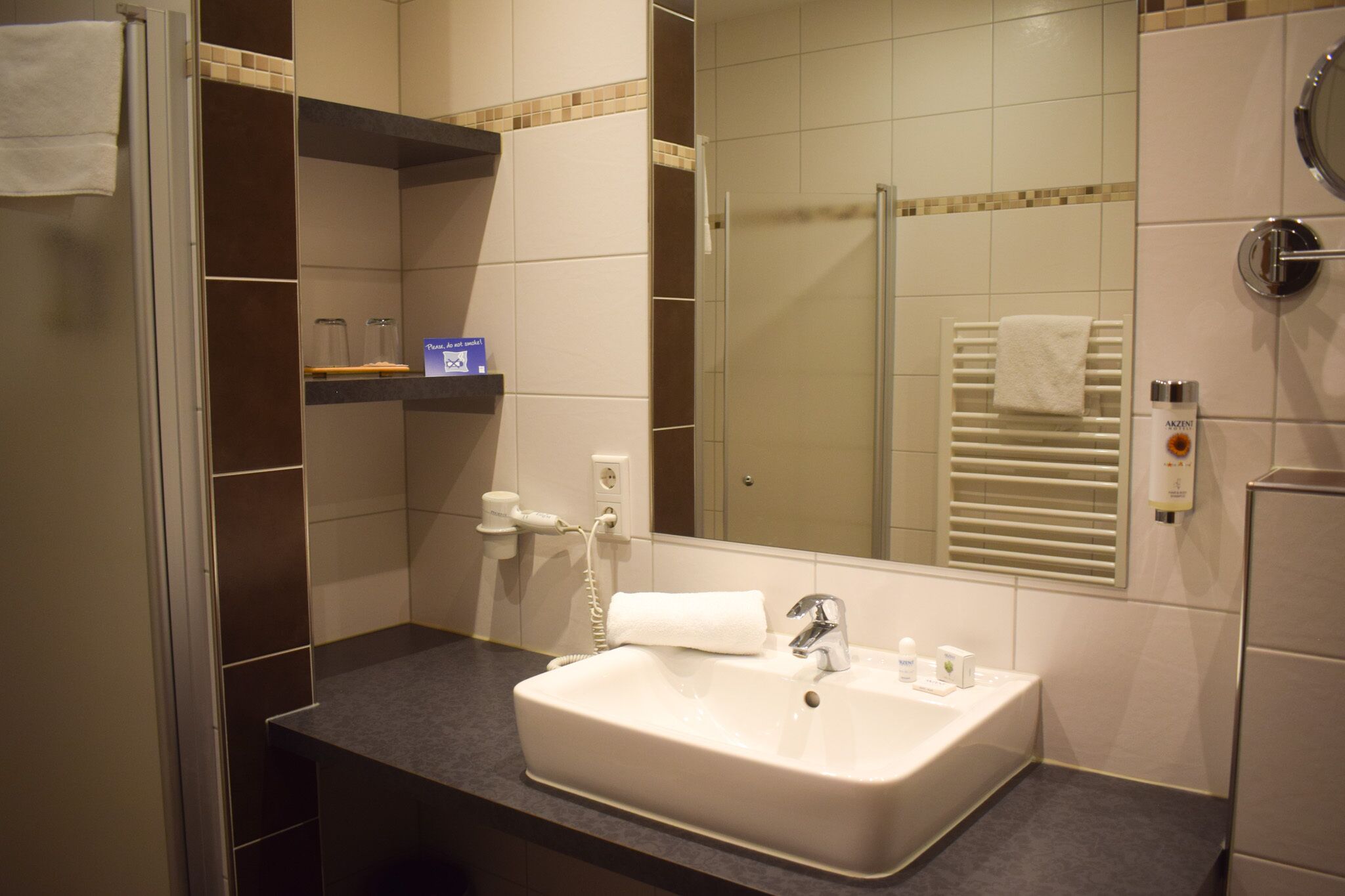 Un baño con lavamanos, espejo, toallero y zona de ducha.