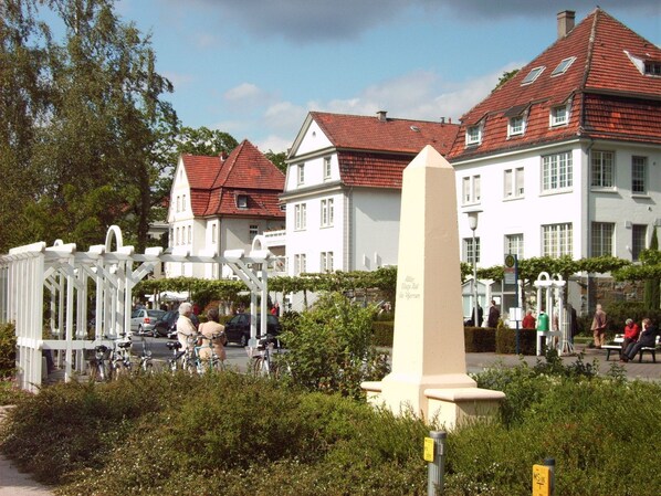 A white building with a red-tiled roof, surrounded by greenery and a white gazebo.