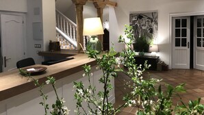 A modern kitchen with a wooden countertop, a green vase, and a staircase in the background.