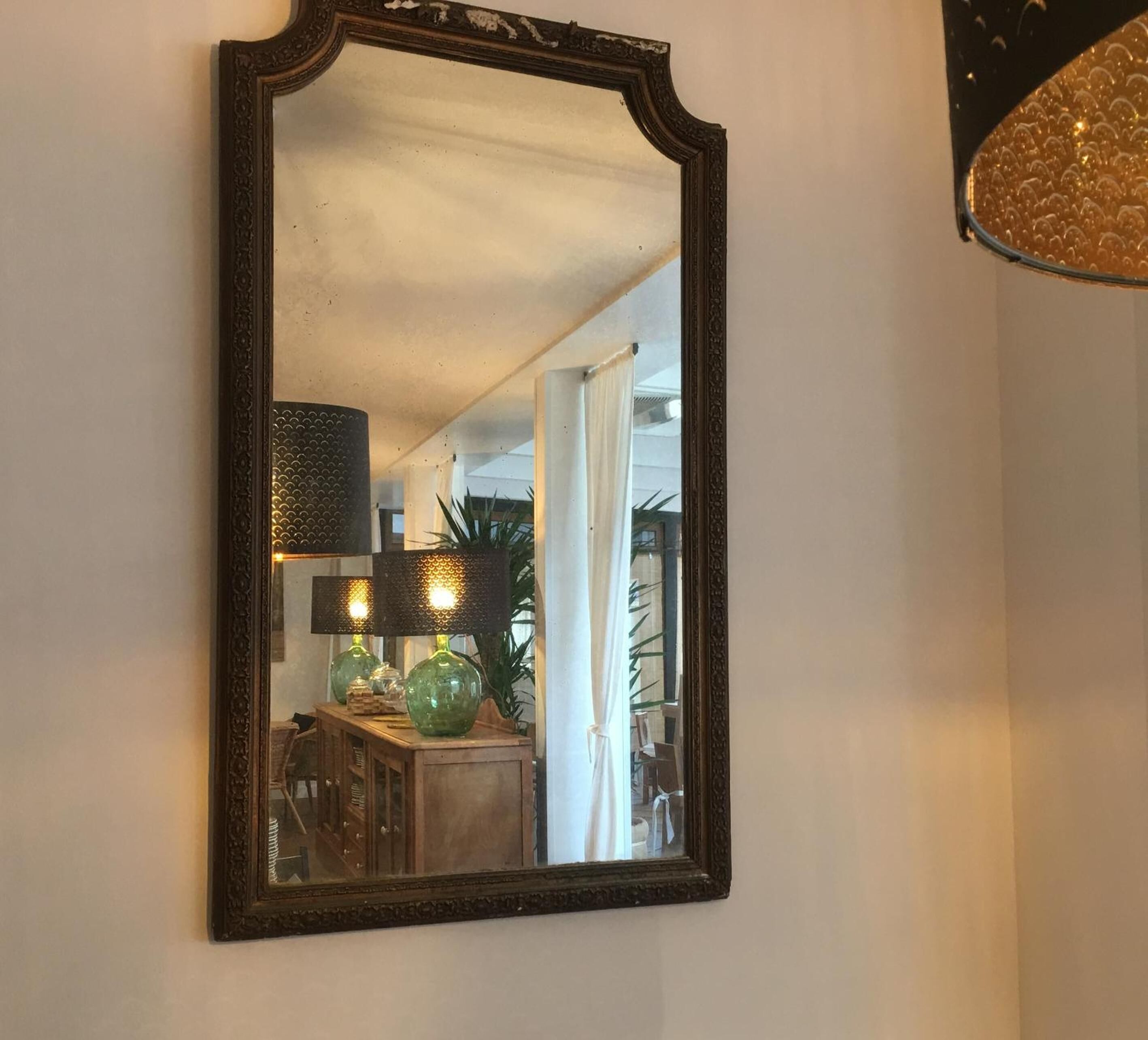 Un miroir avec un cadre orné, accroché au mur.