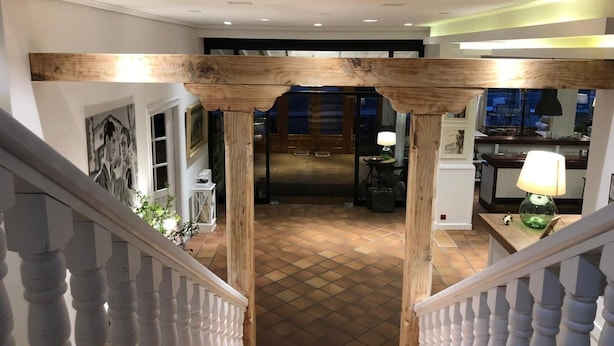A spacious hallway with a wooden staircase leading to a dining area.