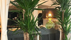 A room with a dark wooden partition, a green potted plant, and a table lamp with a patterned lampshade.