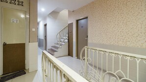A staircase with a white railing, a beige patterned wall, and a door with a sign. - Permata Inn (Medan)