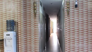 A corridor with tiled walls, a water dispenser, and a door at the end. - Permata Inn (Medan)