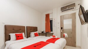 A hotel room with two beds, a mirror, an air conditioning unit, and a television. - Permata Inn (Medan)