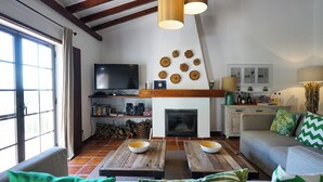 A cozy living room with a fireplace, wooden coffee table, and a television. - Vale Fuzeiros Nature Guest House (Silves)