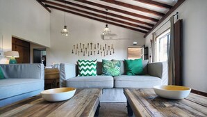 A cozy living room with a sofa, two wooden tables with bowls, a wall with hanging keys, and a wooden ceiling. - Vale Fuzeiros Nature Guest House (Silves)