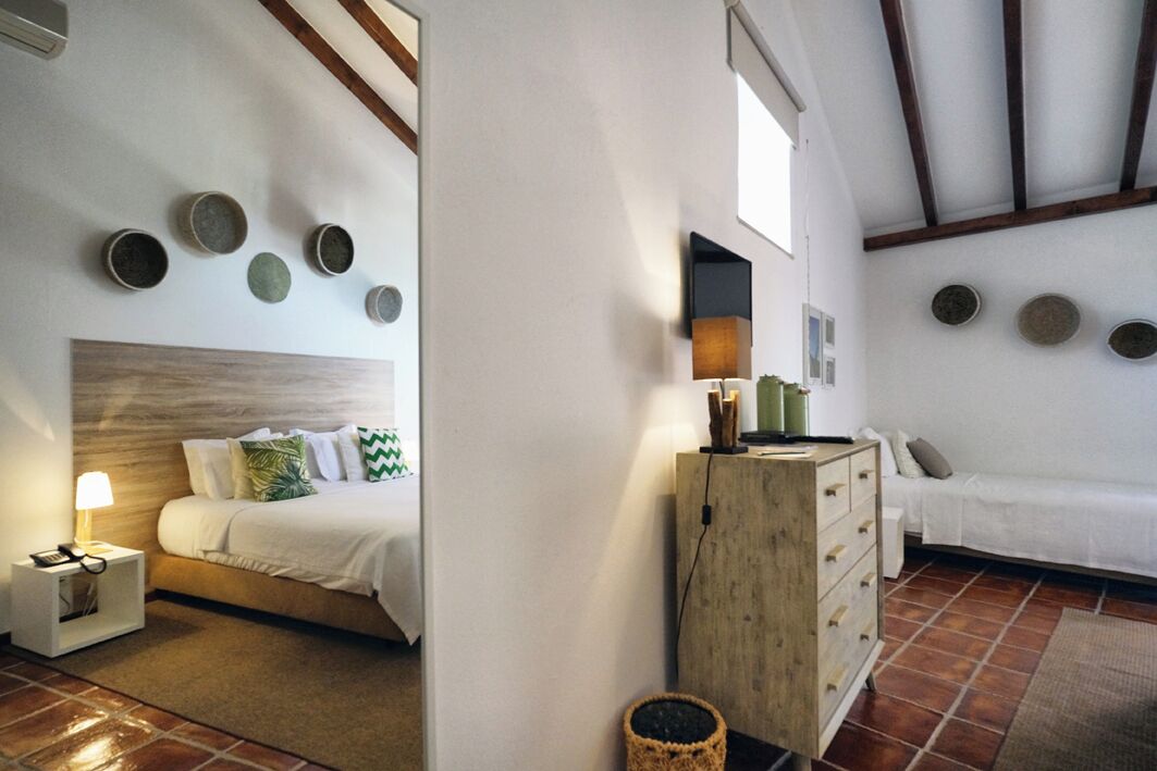 A bedroom with a bed, bedside table, lamp, dresser, and a wall with circular decorations.