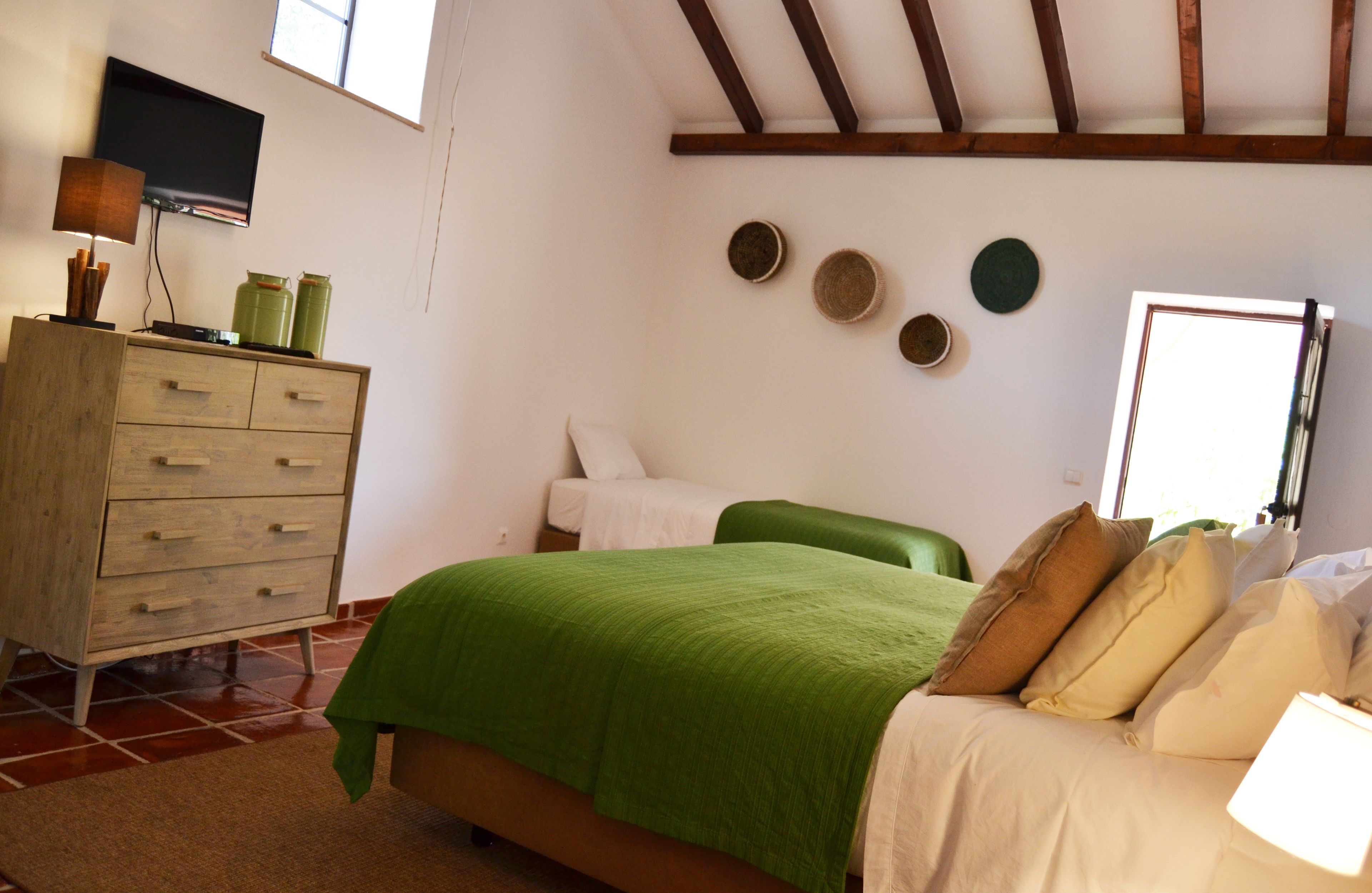 A bedroom with a bed, a dresser, a television, and a window.