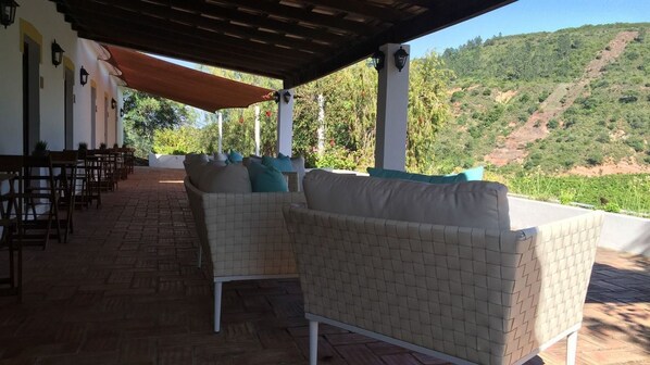 A covered outdoor seating area with wicker furniture and a view of a hillside. - Vale Fuzeiros Nature Guest House (Silves)