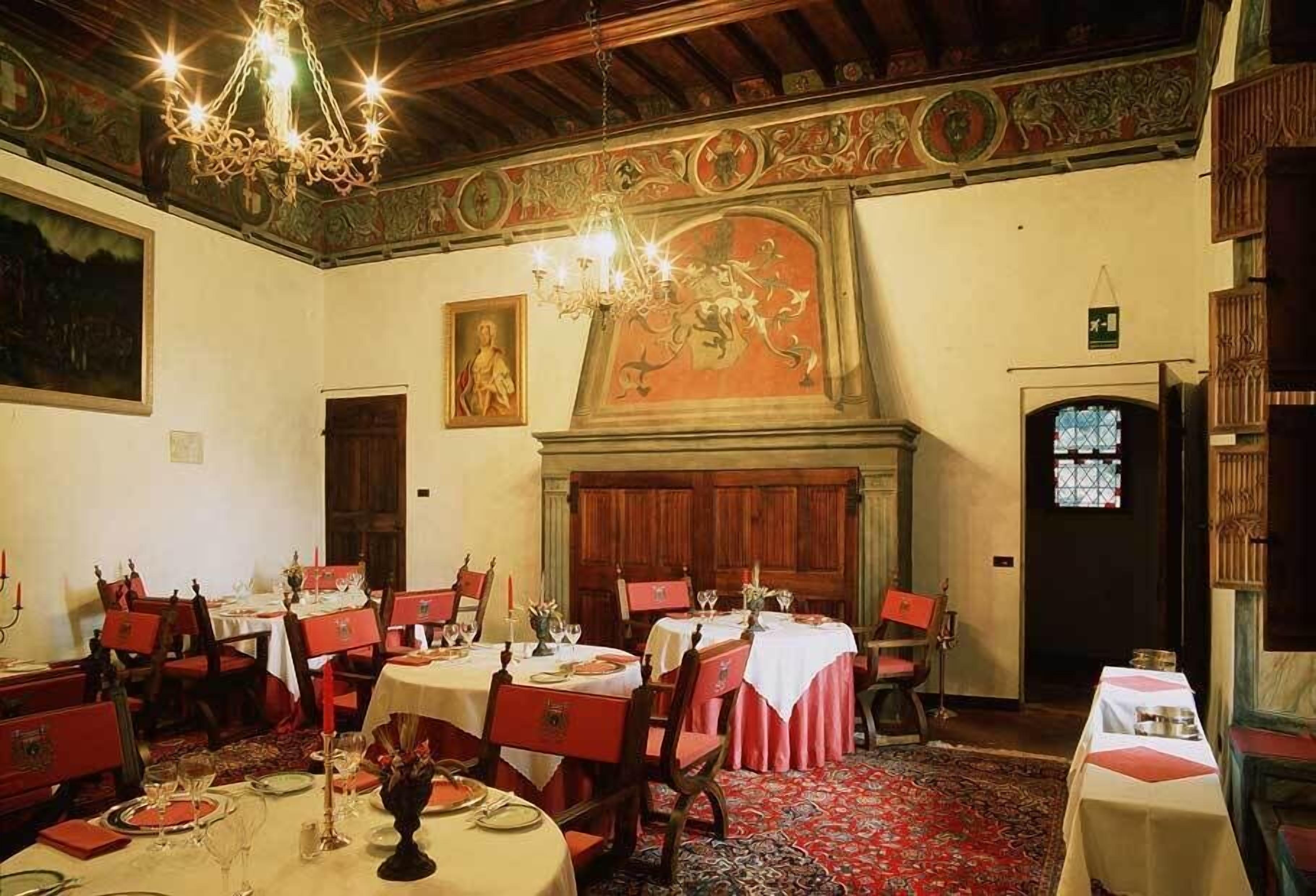 A dining room with multiple tables set for meals, a chandelier, and a fireplace.