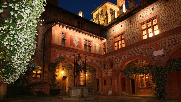 A historic courtyard with brick architecture, arched walkways, and a fountain. - Castello di Pavone (Pavone Canavese)