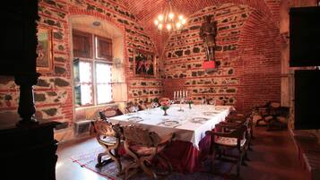 Ein Esszimmer mit Backsteinwand, einer Kristallleuchter und einem Tisch für sechs Personen.