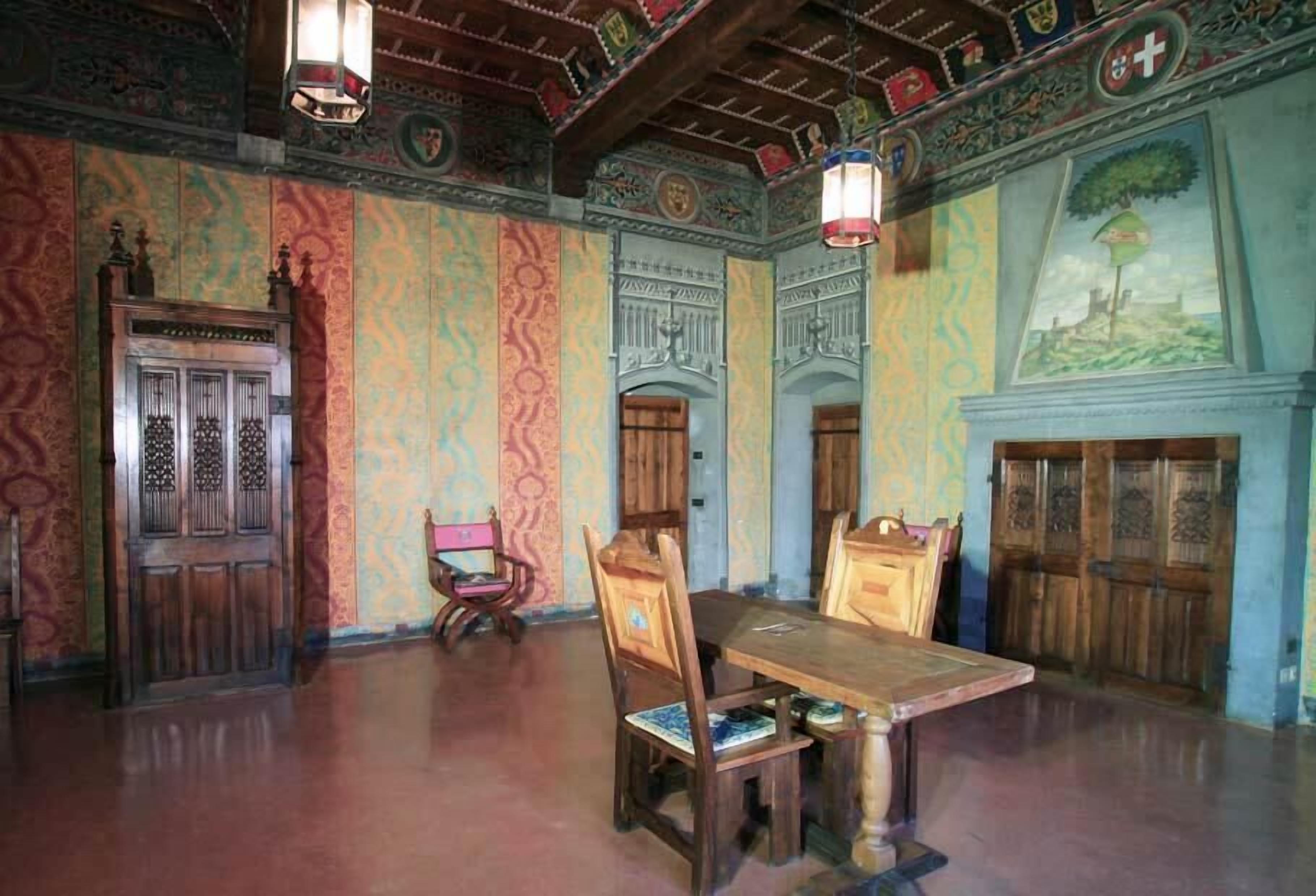 Comedor con mesa y sillas de madera, techo ornamentado y paredes con diseños.