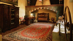 A room with a large ornate wooden cabinet, a wooden bench, a red patterned rug, and a stone fountain. - Castello di Pavone (Pavone Canavese)