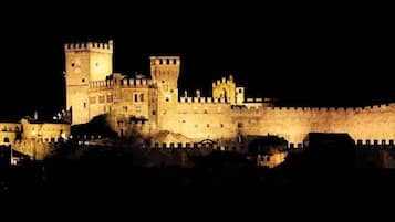 Una gran estructura iluminada que se asemeja a un castillo, con múltiples torres y un muro fortificado.