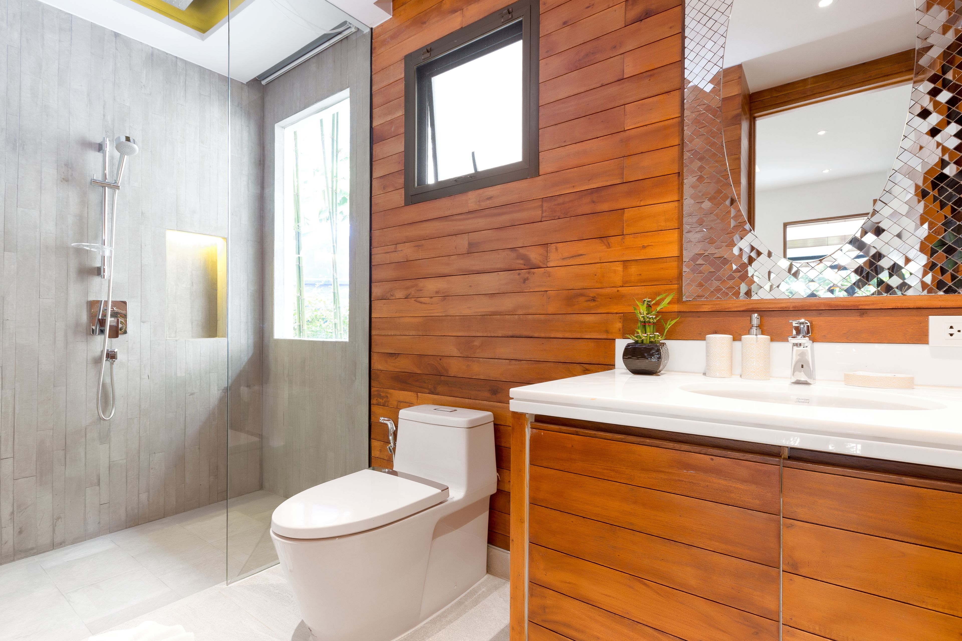A modern bathroom with a wooden vanity, a glass shower enclosure, and a toilet.