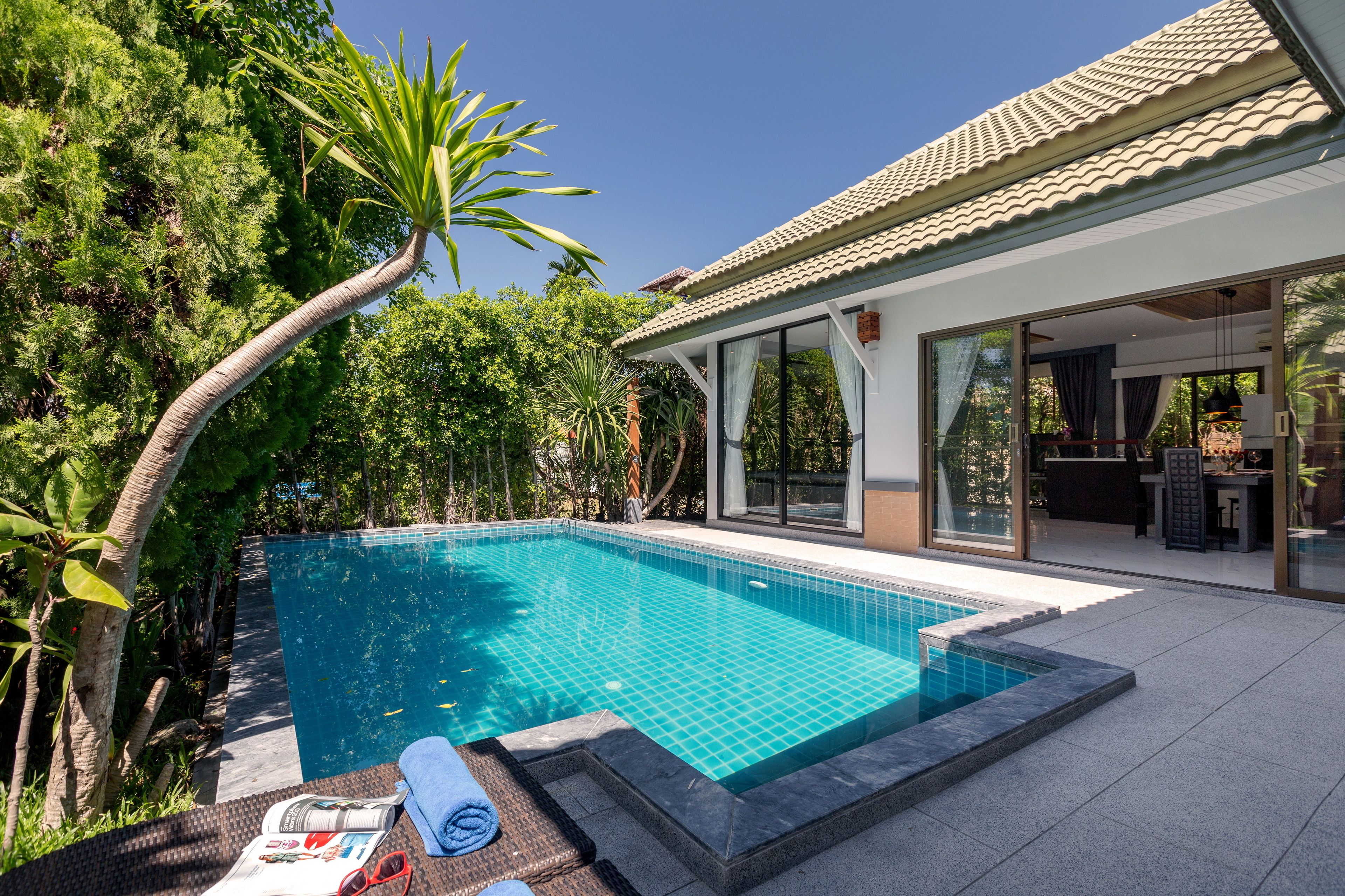 A modern house with a swimming pool surrounded by lush greenery.