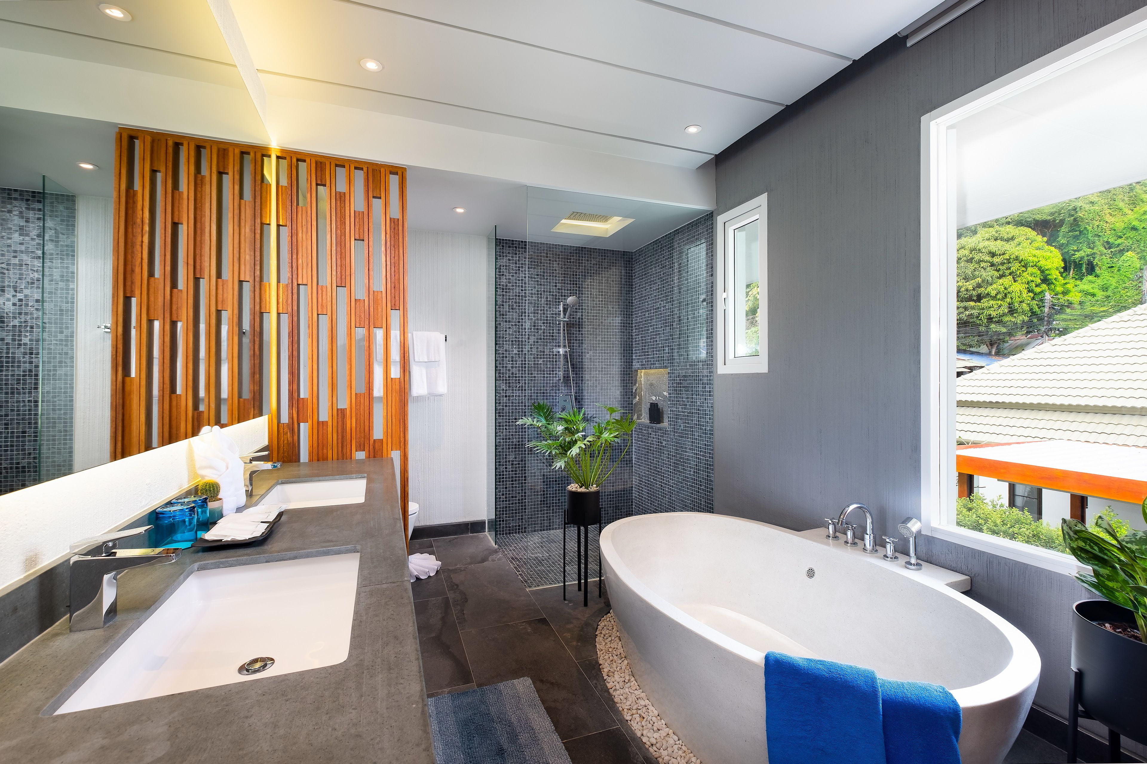 A modern bathroom with a large bathtub, a double sink, and a shower area.