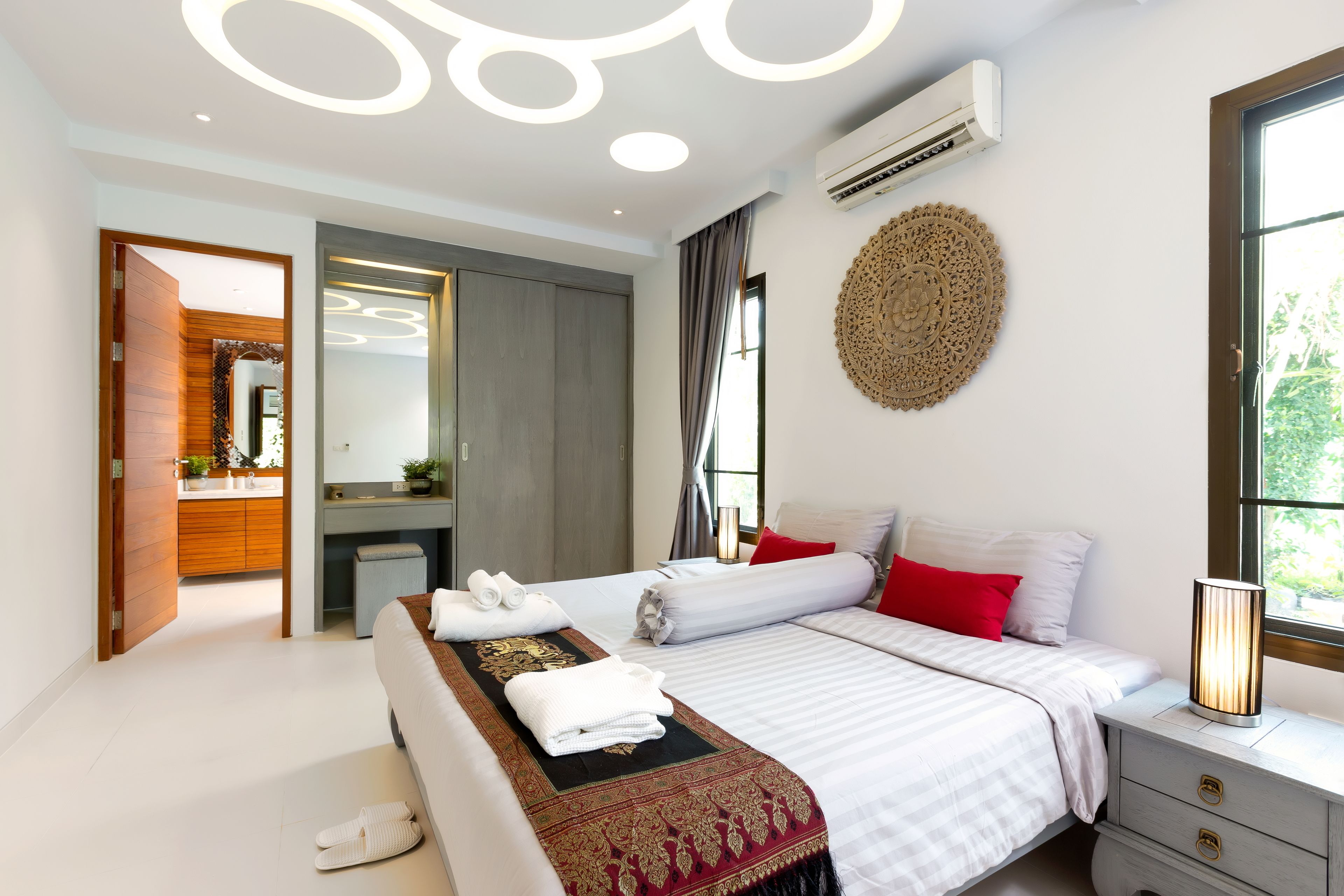 A modern hotel room with a large bed, a bedside table, a mirror, and a window with curtains.