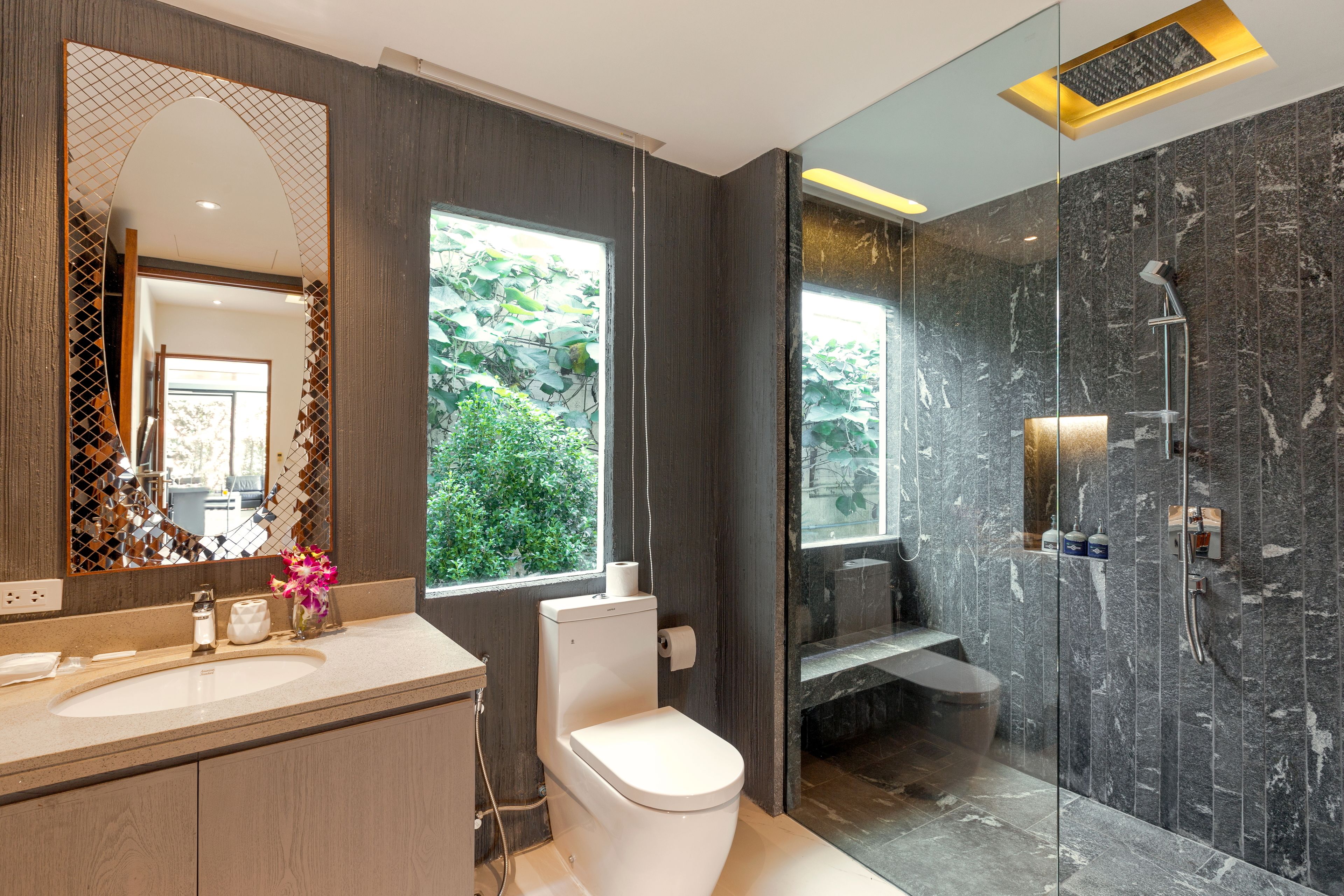 Ein modernes Badezimmer mit großem Spiegel, Toilette, Waschbecken und Duschbereich.