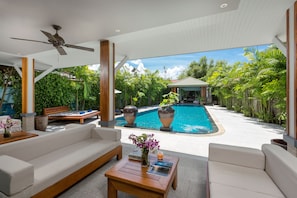 A poolside area with a ceiling fan, outdoor seating, and a view of a swimming pool. - Karon Beach Pool Villa (Karon)