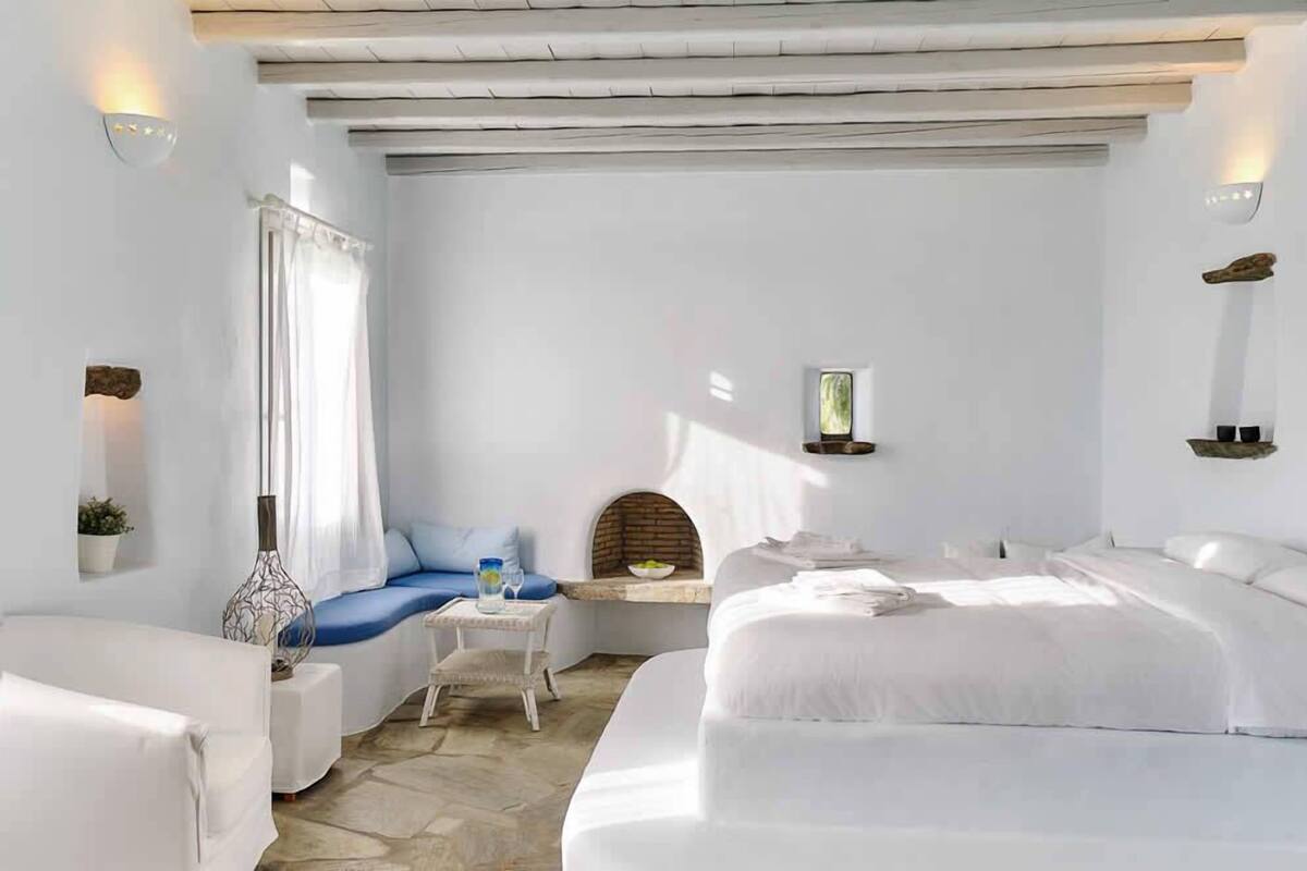 A modern, minimalist bedroom with a large bed, a smaller sofa, and a small table.