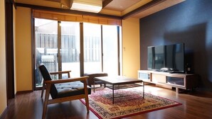 A modern living room with a large flat-screen TV, a sofa, a coffee table, and a patterned rug. - Horikawakoji Umenotoan (Kyoto)