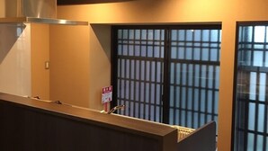 A hotel lobby with a reception desk, a large window with a grid pattern, and a ceiling with recessed lighting. - Horikawakoji Umenotoan (Kyoto)