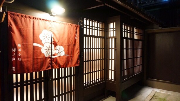 A traditional Japanese room with tatami flooring, shoji screens, and a hanging shifu with a floral design. - Horikawakoji Umenotoan (Kyoto)
