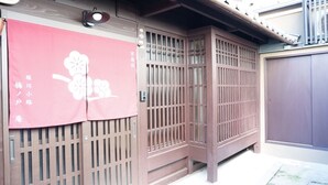 A traditional Japanese gate with a pink decorative cloth featuring a floral design and Japanese text. - Horikawakoji Umenotoan (Kyoto)