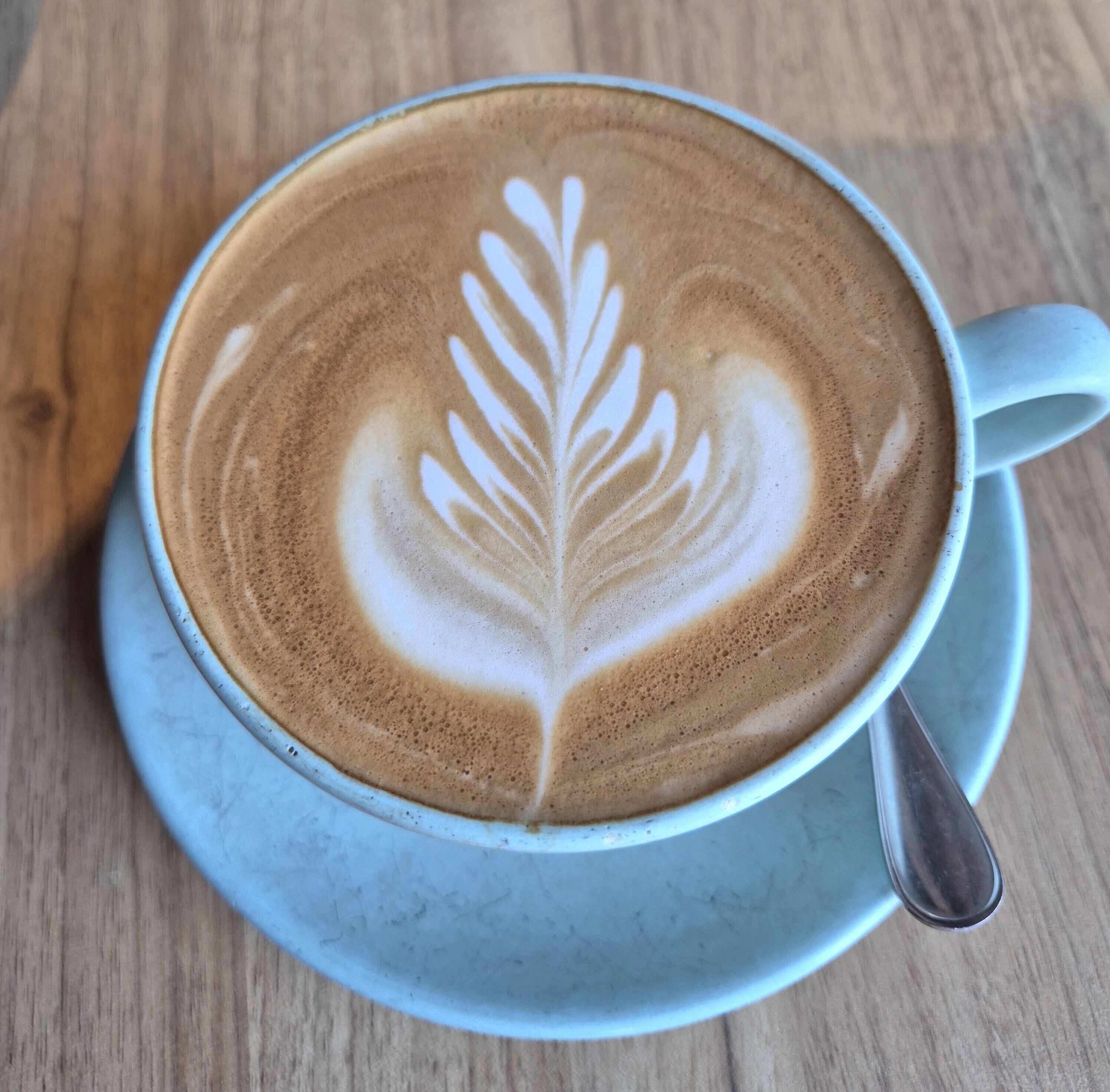 A cup of coffee with latte art on a saucer.