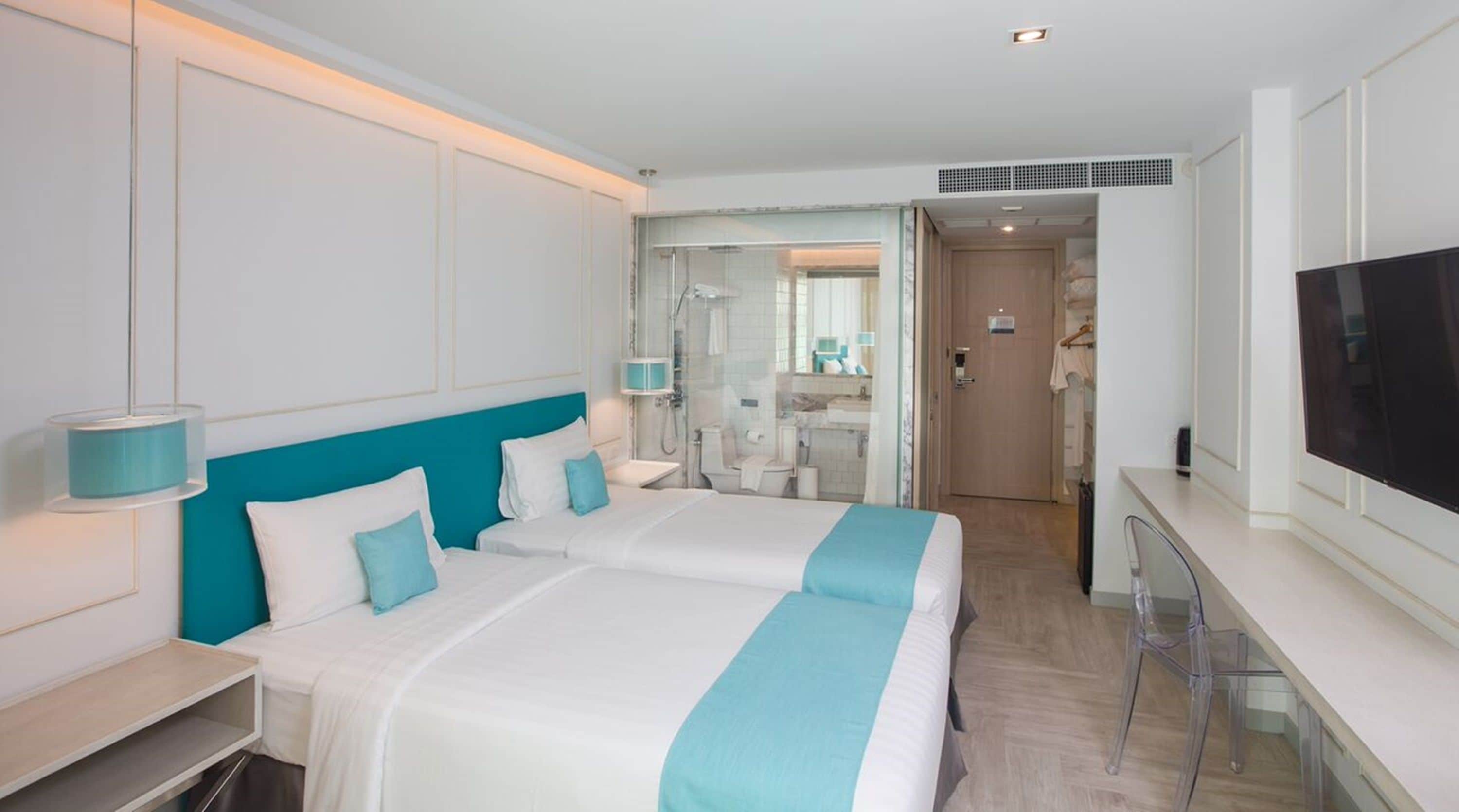 A hotel room with a large bed, a TV, a desk, and a bathroom with a shower and toilet.