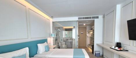 A hotel room with two beds, a bathroom, and a TV on the wall.