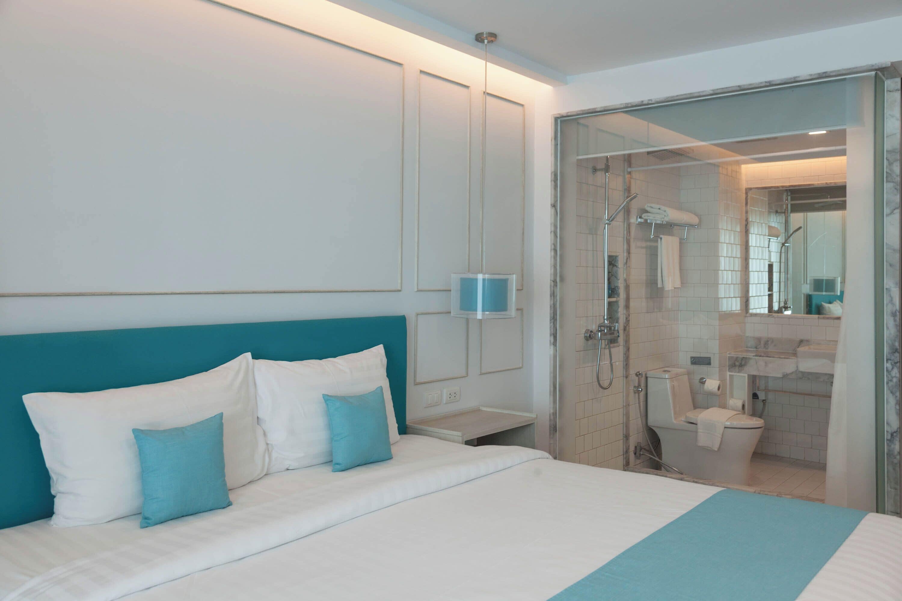 Una habitación de hotel moderna con una cama grande, cabina de ducha de vidrio y baño a la vista.