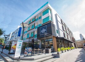 Un edificio moderno con una cafetería en la planta baja, mesas al aire libre y un letrero que dice The Bloc Hotel.
