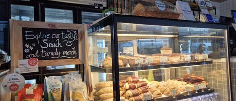 Mostrador de una panadería con diversos productos horneados y un letrero que anuncia croissants recién hechos.