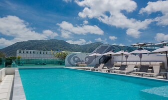 Una piscina con sillas de descanso y sombrillas, rodeada por un paisaje montañoso.