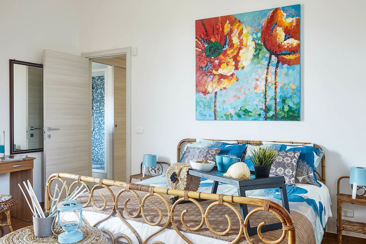 Quarto com cama, mesa de cabeceira e uma grande pintura na parede.