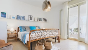 A bedroom with a bed, bedside table, lamp, and wall art. - Villa Marina Green CaseSicule (Pozzallo)