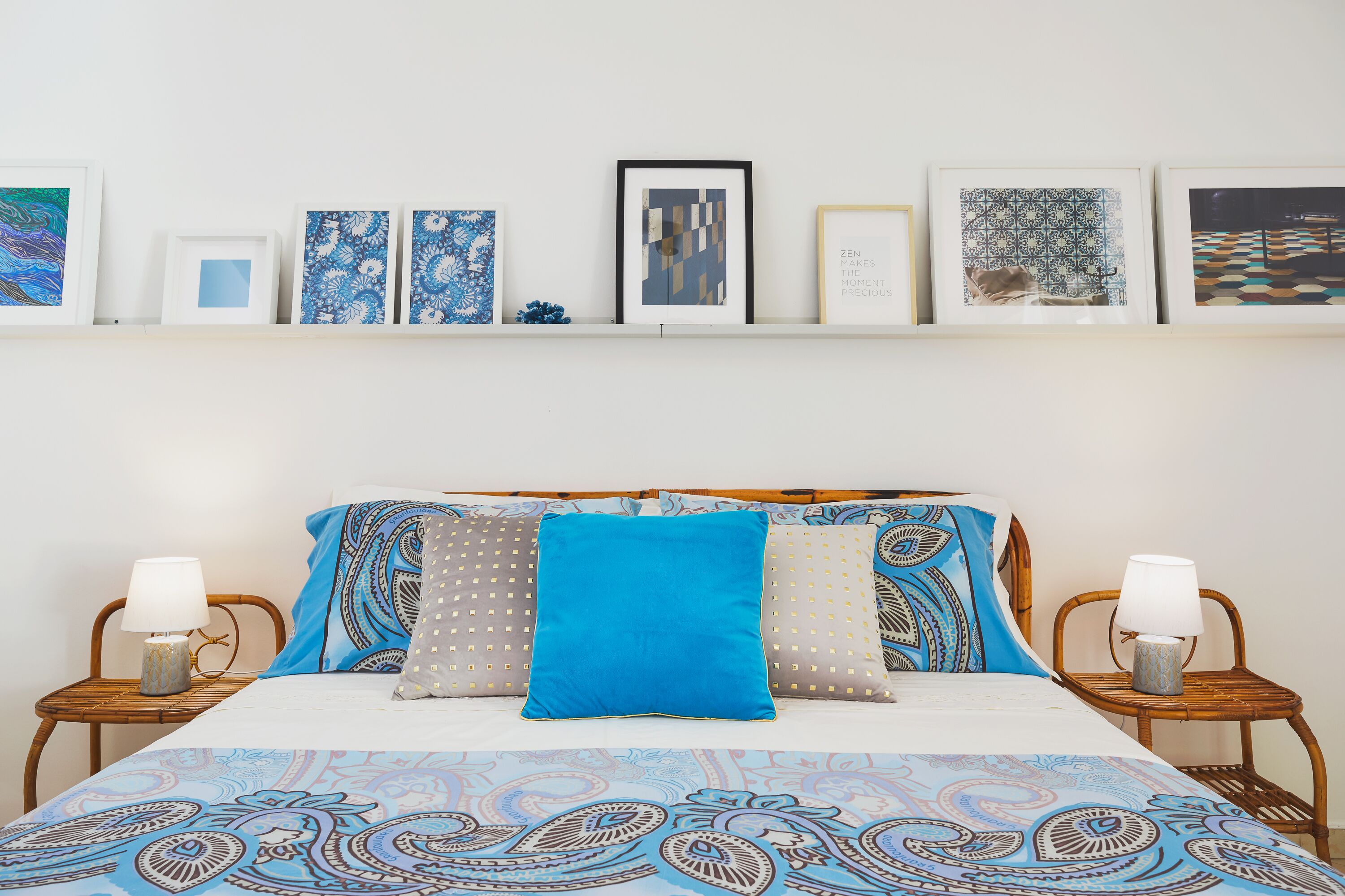 A neatly arranged bedroom with a bed, two bedside tables, and a wall decorated with framed artwork.
