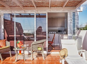 A modern outdoor patio with wicker furniture, a dining table, and a white lounge chair. - Villa Marina Green CaseSicule (Pozzallo)