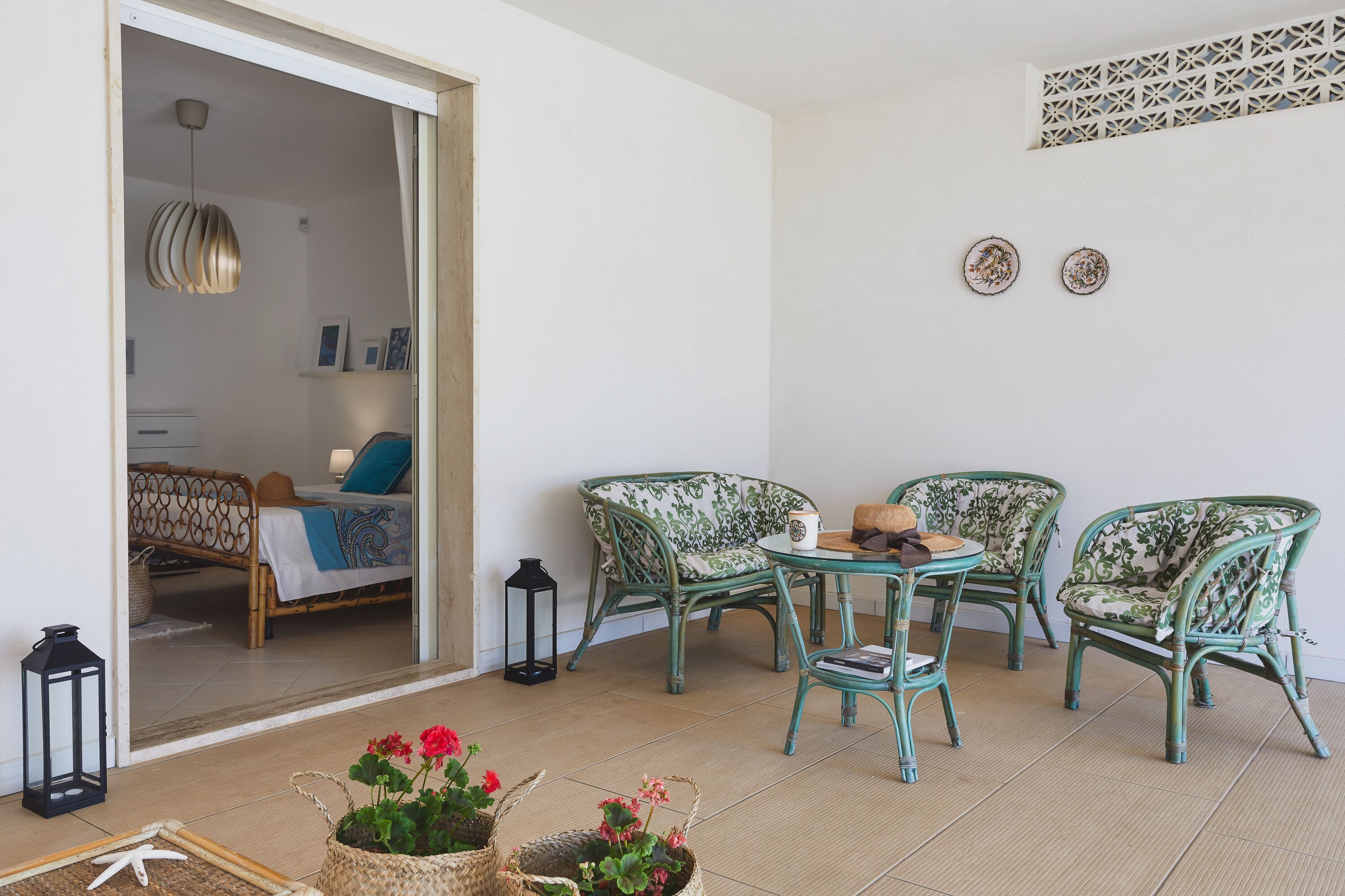 A room with a bed, two chairs, a table, and a potted plant.