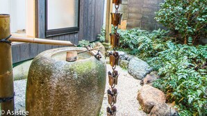 Een traditionele Japanse tuin met een stenen lantaarn, een houten hek en een houten gebouw met een schuifdeur.