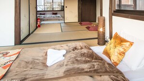 Een traditionele Japanse kamer met tatami vloerbedekking, een futon bed, een shoji schuifwand en uitzicht op buiten.